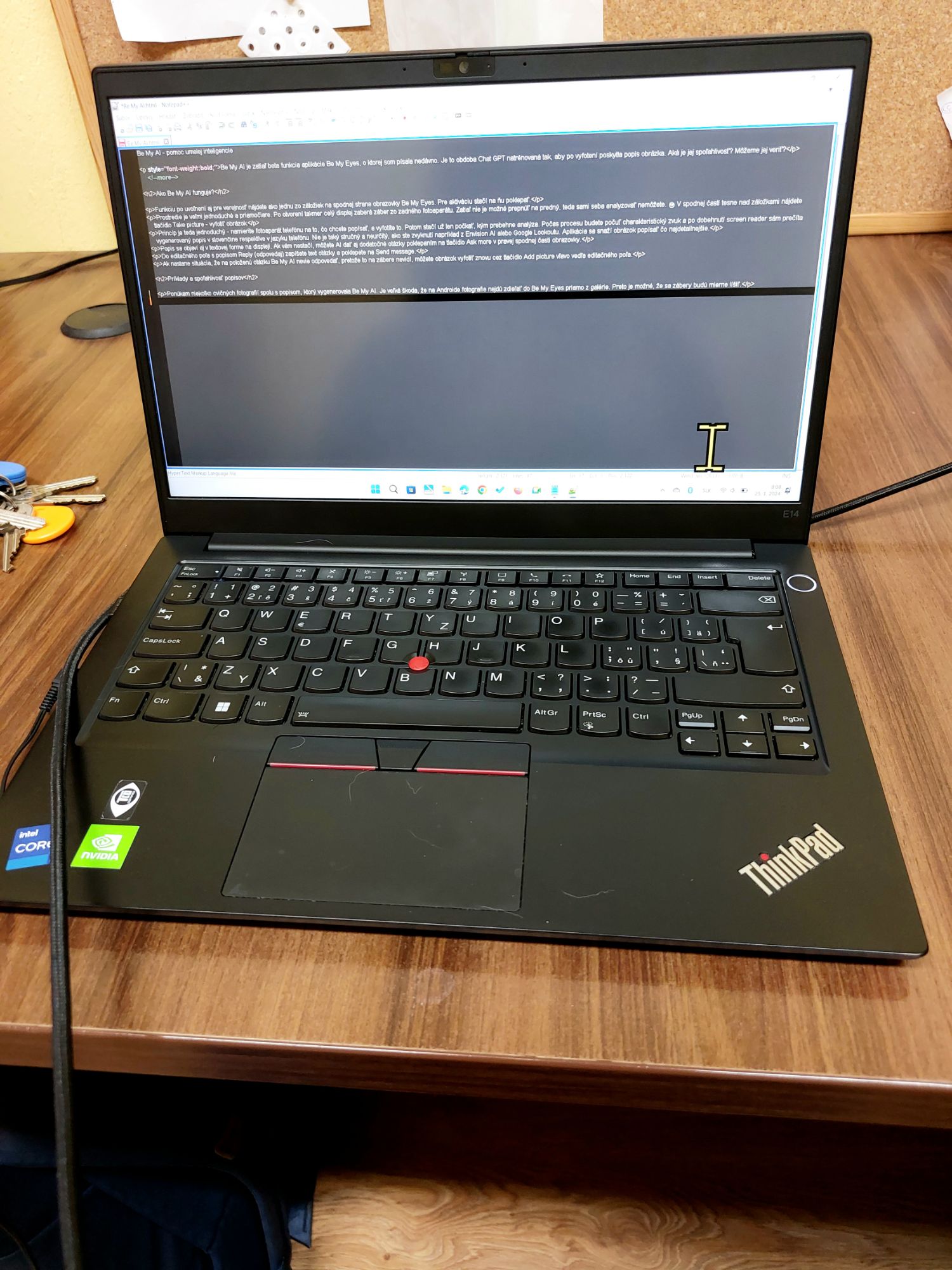 Čierny notebook položený na hnedom drevenom stole, na ktorého displeji je otvorený Notepad++ s článkom o Be My AI.